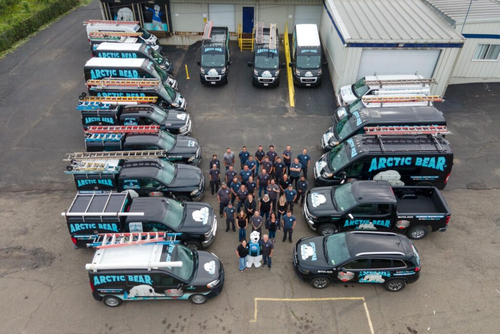 Arctic Bear team posing for aerial drone shot with company trucks surrounding them
